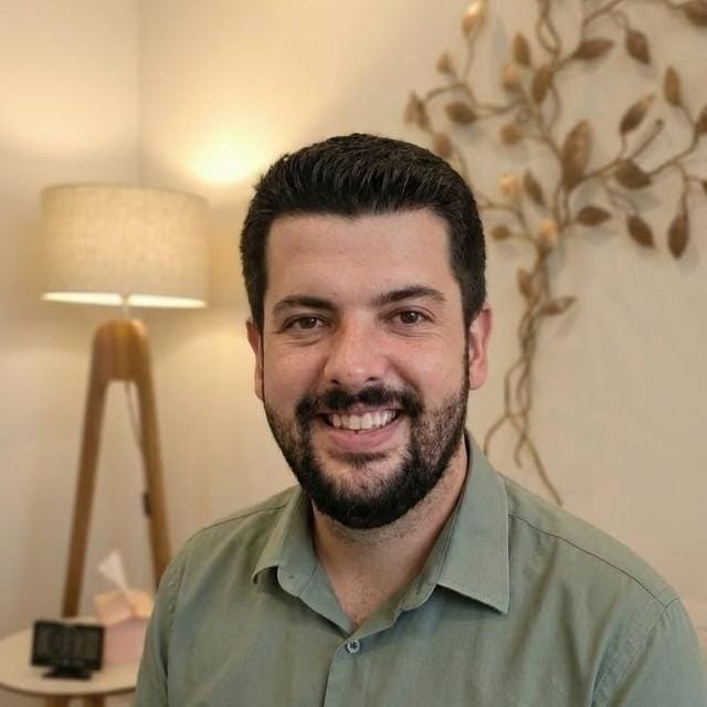 Danilo Melo, psicólogo, sorrindo em seu consultório em Campinas